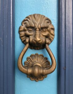 A blue door with a gold lion door knocker on it